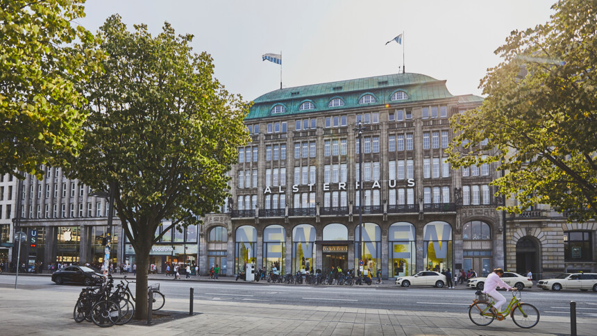 Das historische Alsterhaus Kaufhaus in Hamburg mit Fahrrädern und Passanten im Vordergrund.