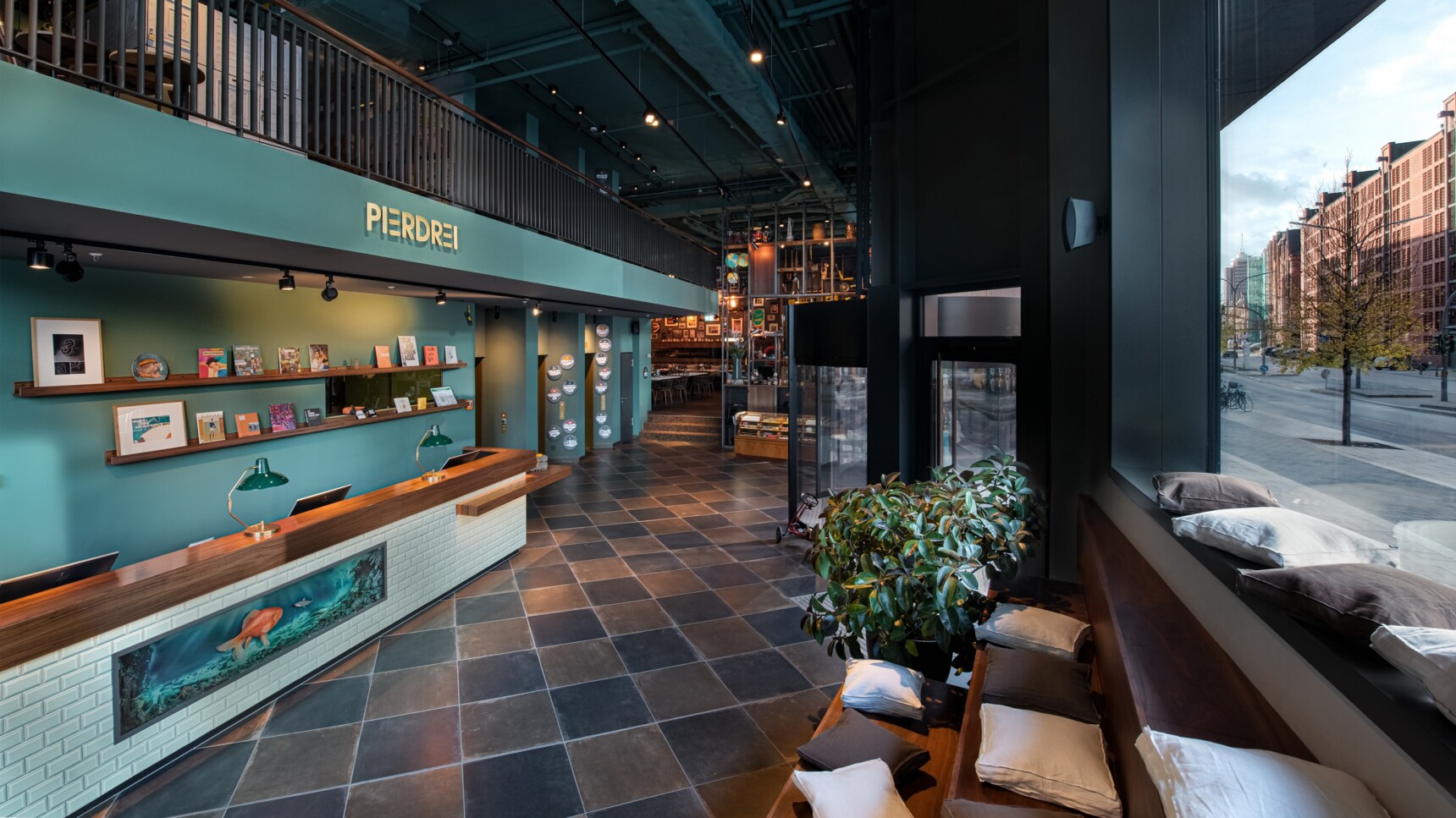 Innenansicht der modernen Lobby mit Rezeption, Sitzbereich und großem Fenster mit Blick auf die Straße.