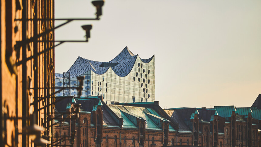 Blick auf die Elbphilharmonie mit historischen Speichergebäuden im Vordergrund bei Sonnenuntergang.