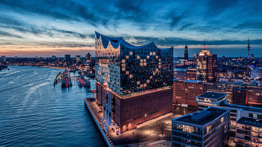 Blick auf die Elbphilharmonie und den Hamburger Hafen bei Abenddämmerung.